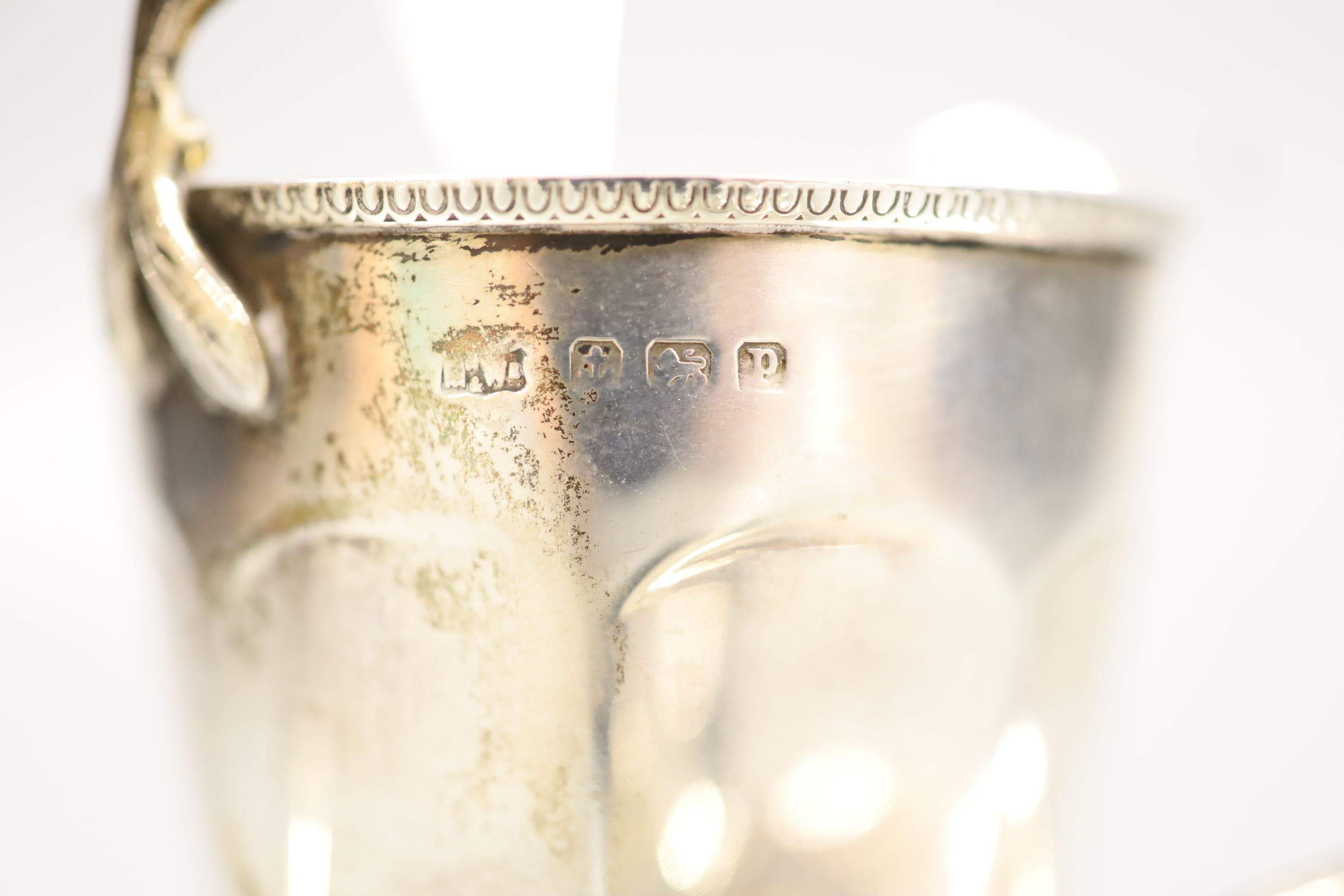 A George V silver helmet shaped cream jug, a silver sugar caster and a sifter spoon (3)